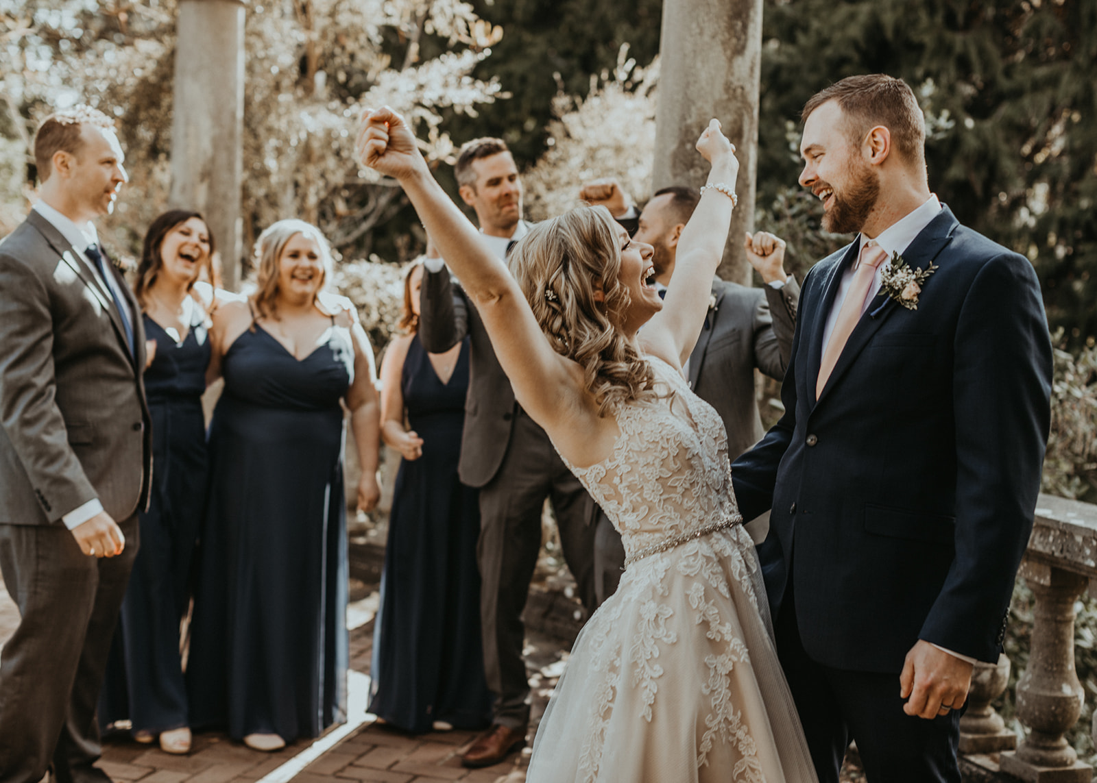 Bride throws her arms up in happiness wearing Rebecca Ingram gown by Blush Bridal Vancouver Island