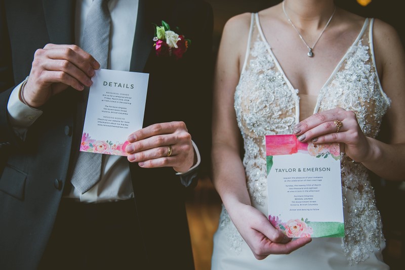 Newlyweds hold pink and coral invite cards by Tickle Tree Designs Vancouver Island
