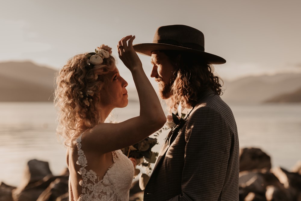 Golden Hour bride touching groom's hat lace dress west coast weddings