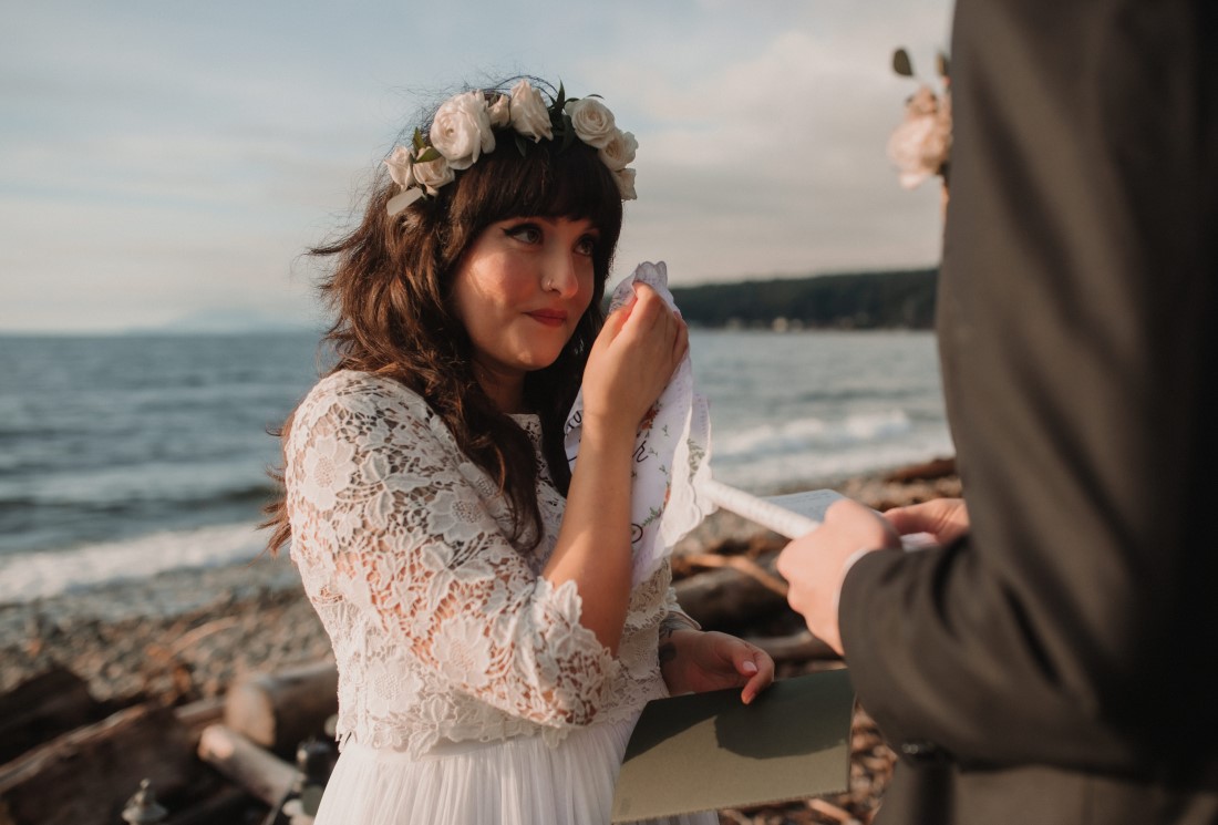 Bride wipes away tears as she exchanges vows at beach wedding ceremony
