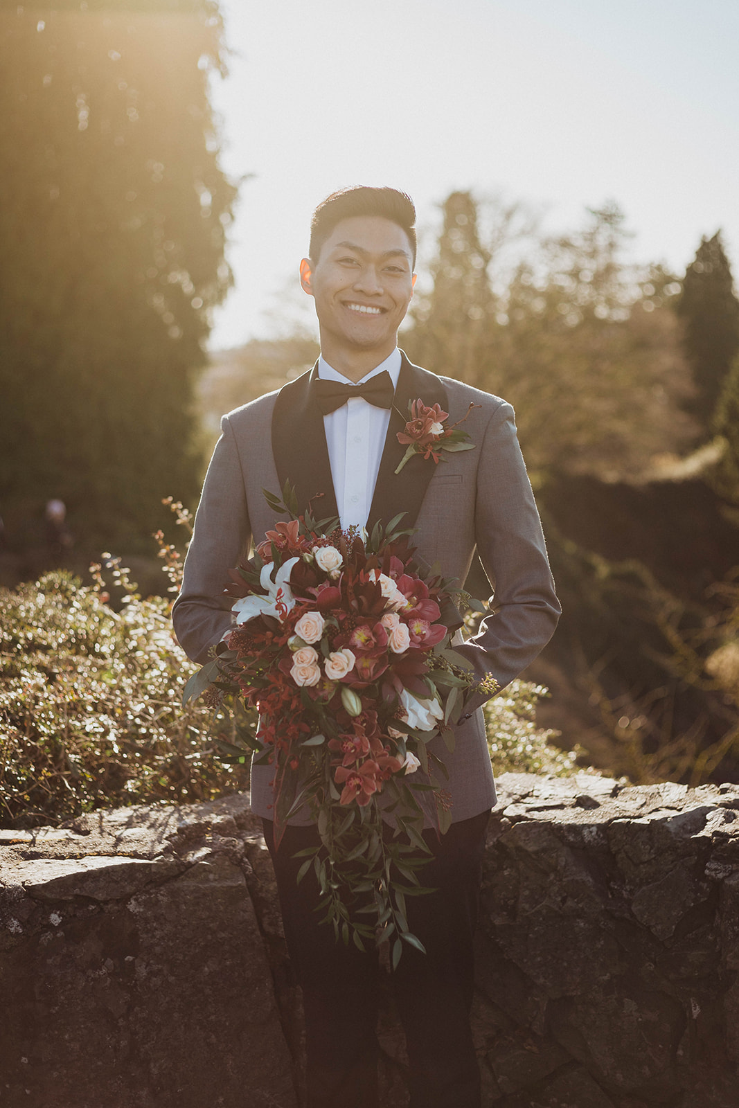 Sumesur groom in blue grey jacket with black lapels holding bridal bouquet by Niki Trading Vancouver