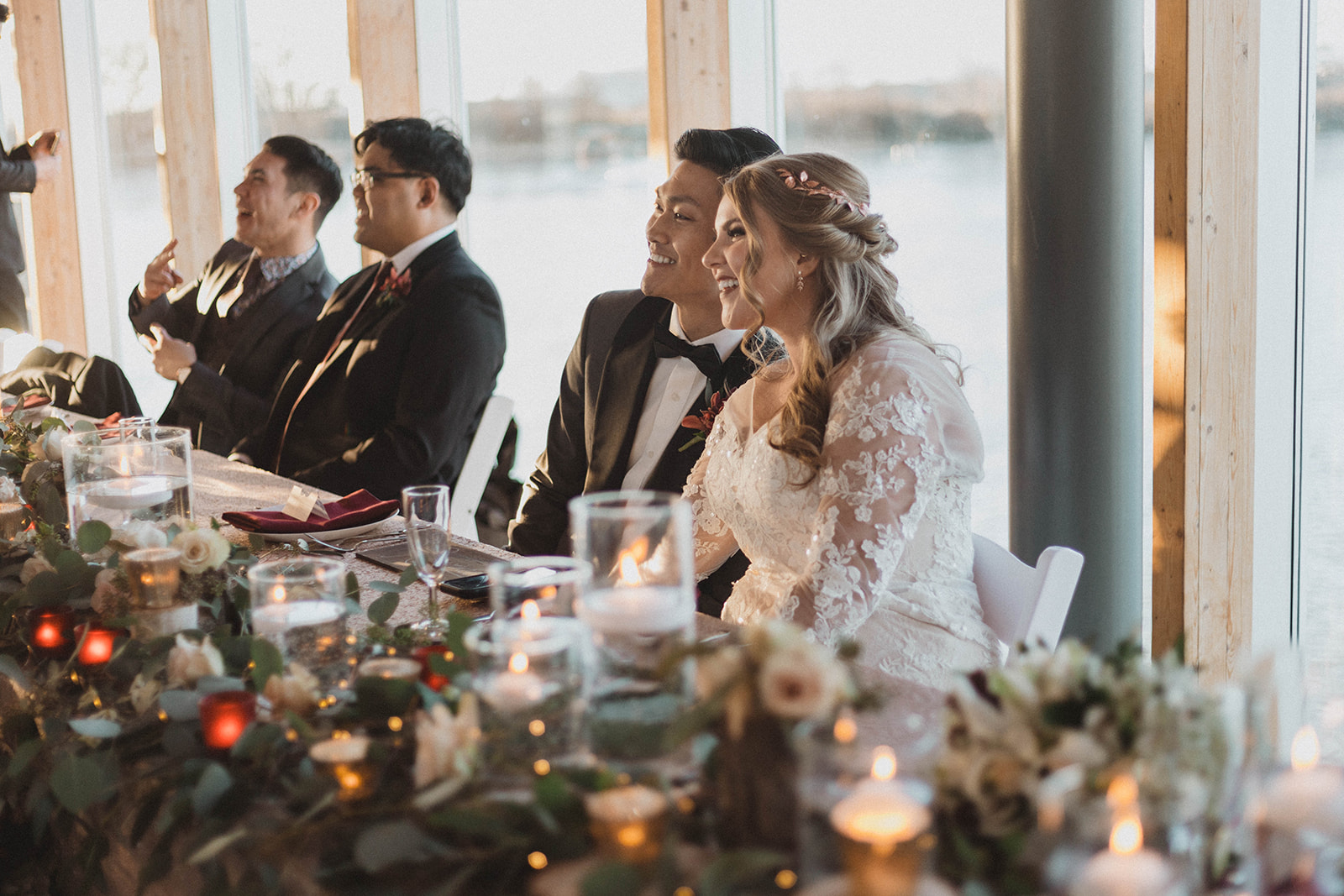 UBC Boathouse Couple sit at head table with Vancouver waterfront behind them by Kacie McColm
