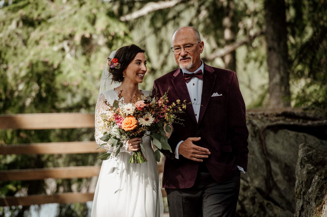 Father walks bride down the aisle at Stone Circle in Whistler with bouquet by Senka Florist