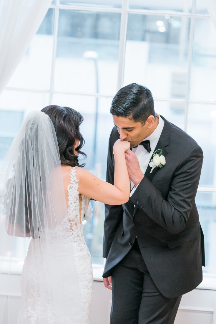 Groom kisses brides hand by L'Estelle Photography