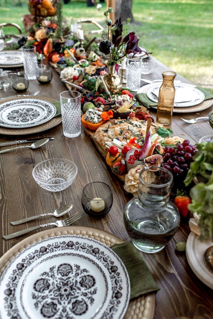 Blue and white plates on wood trestle table with edible centerpiece