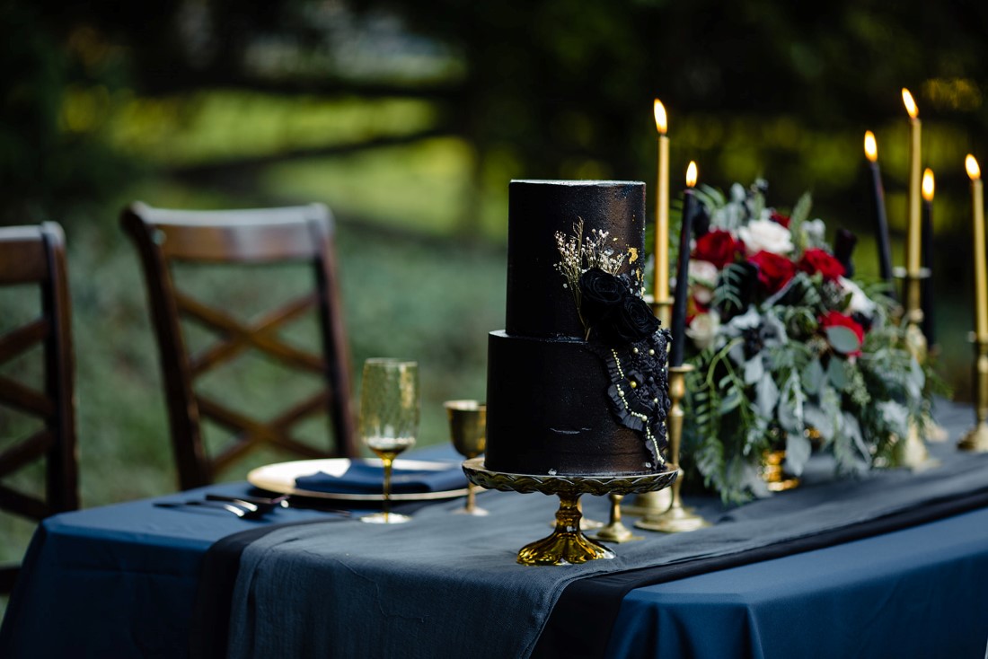 Sweetheart Wedding table with black wedding cake, gold candlesticks and navy linen outdoors in Vancouver