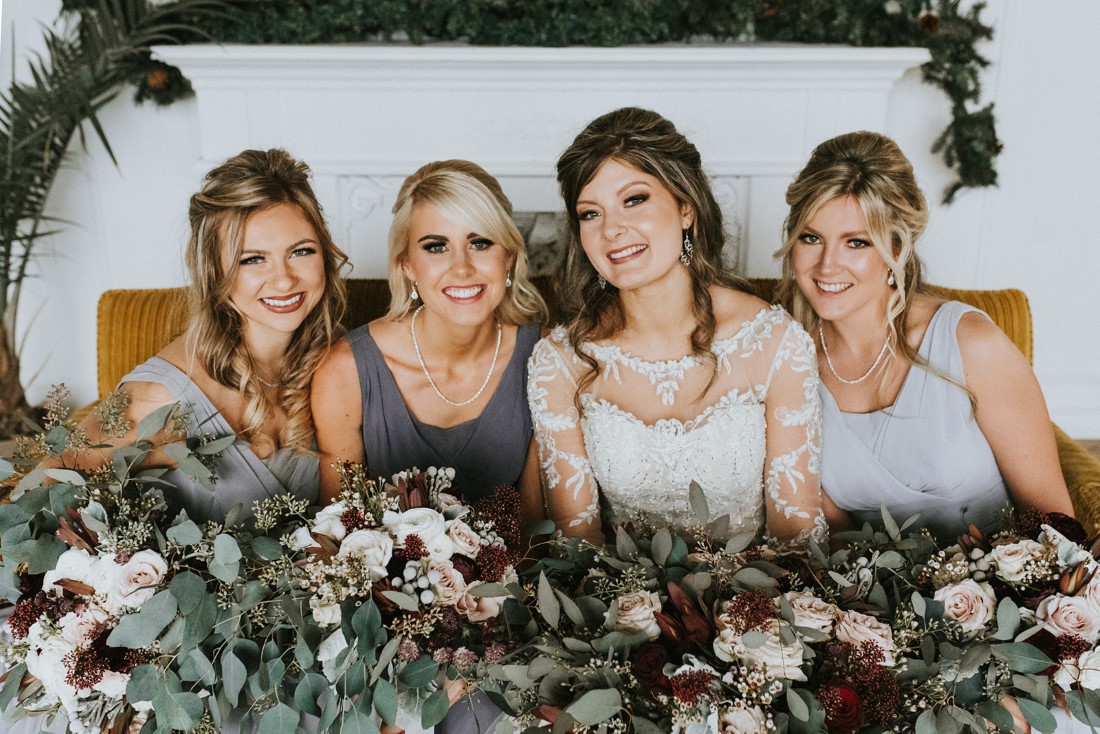 Bride and Bridesmaids hold bouquets of roses, eucalyptus and dusty miller