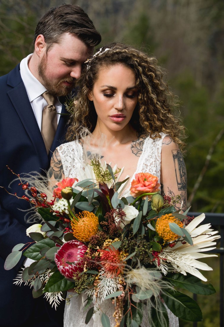 Bridal bouquet of pink protea, yellow mums, pampas grass, eucalyptus and white and peach roses by Maple Ridge Floral Ltd.