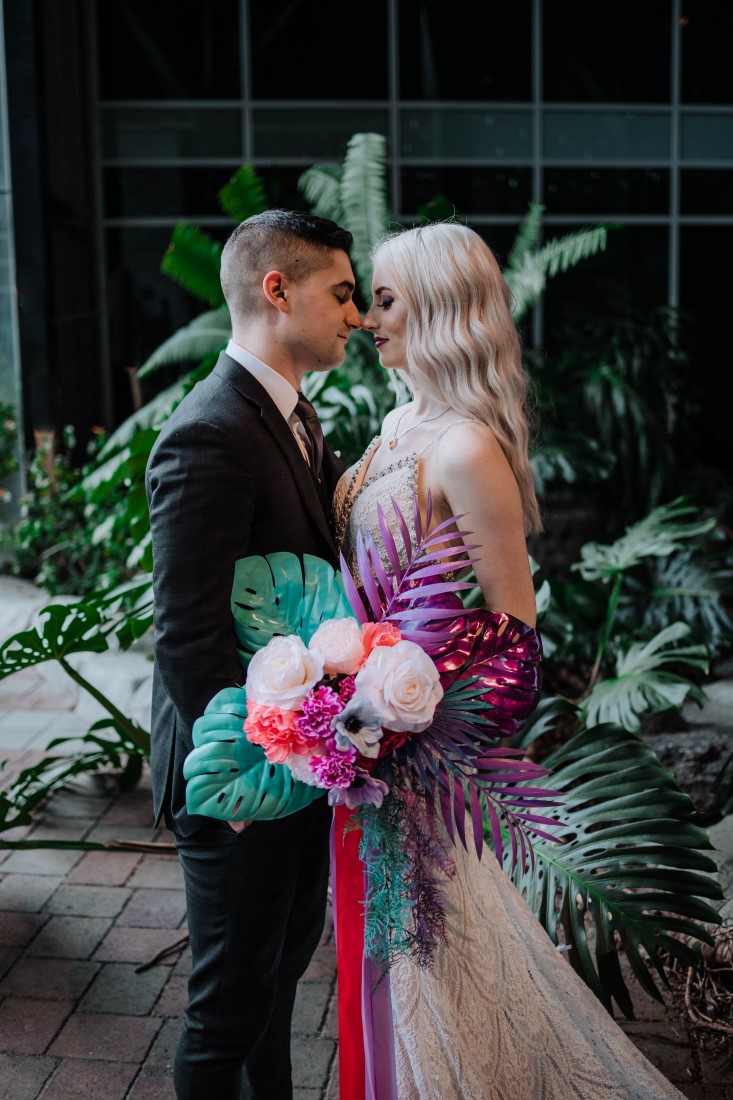 Newlyweds kiss behind the palms in the Parkside Hotel Atrium