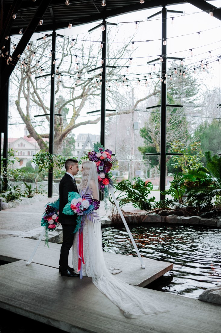 Wedding ceremony in front of triangle backdrop in atrium of Parkside Hotel