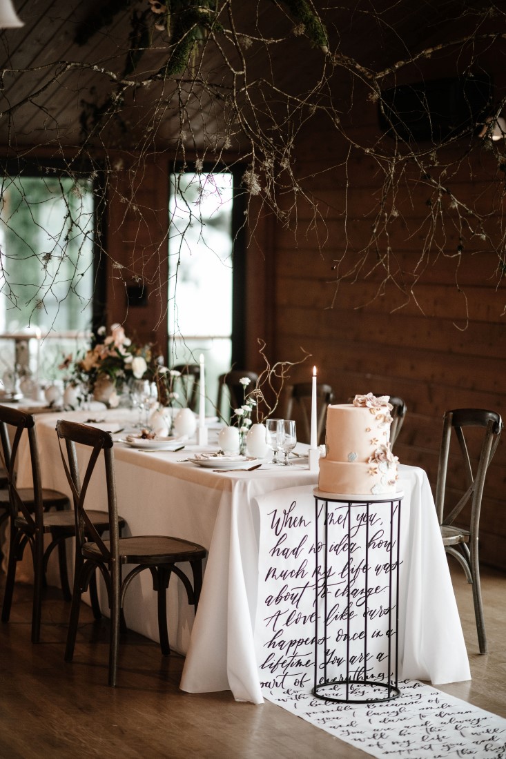 Wedding Cake sitting on calligraphy linen on floor by Bezaire Events