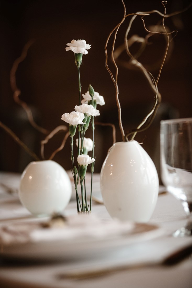White modern vases hold twigs and flowers on wedding reception table at Dolphin's Resort