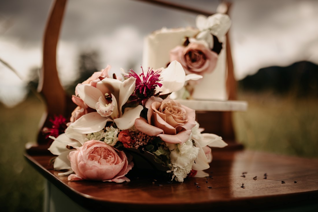 Wedding Cakes sit on vintage dresser in field of flowers on Vancouver Island