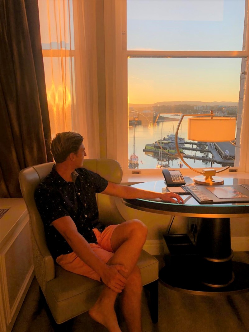 Groom looks out window of Fairmont Empress at Victoria Inner Harbour