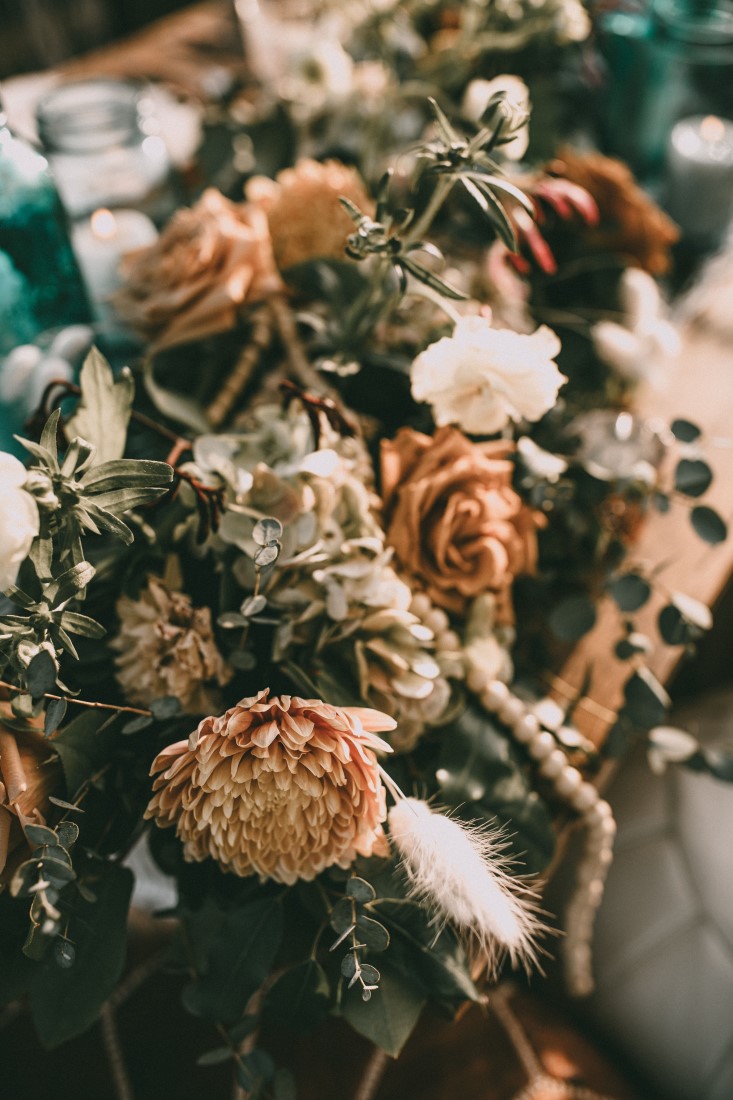 Peach and Ivory roses with beads on wood table 