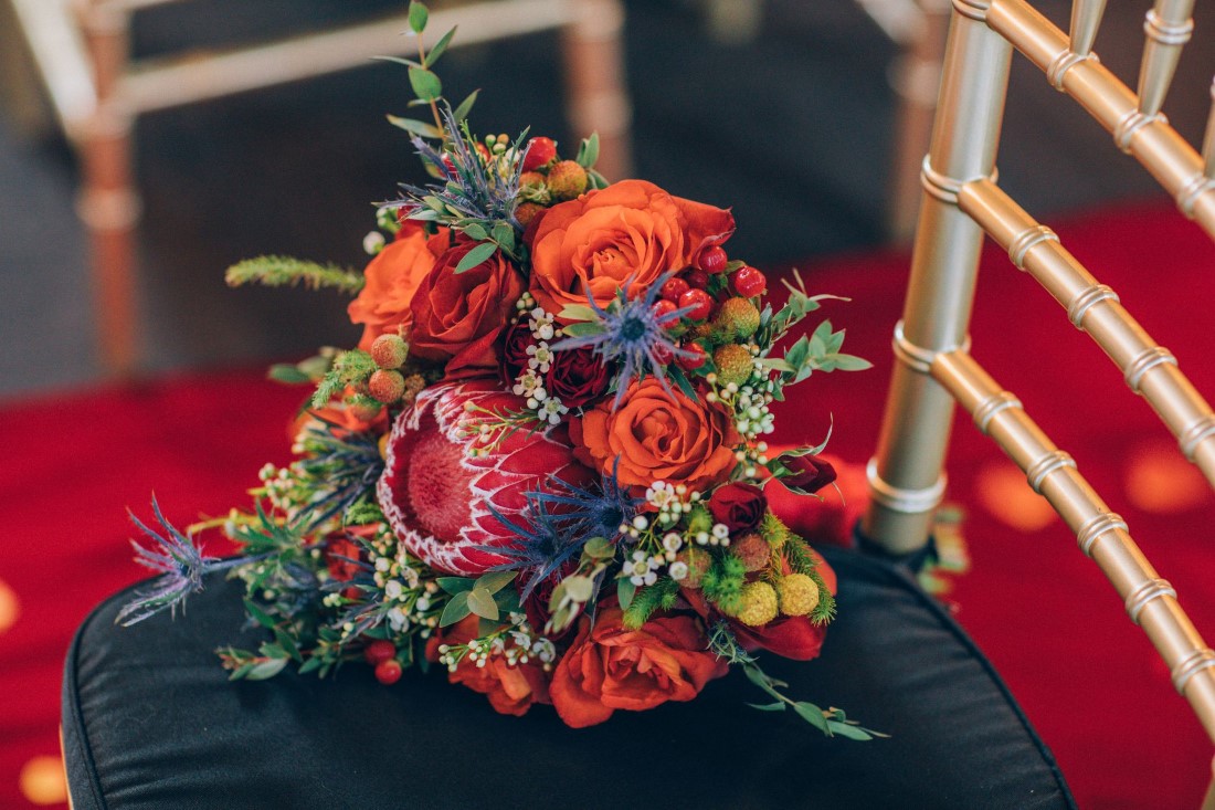 Bridal Floral Bouquet with orange roses and protea on black chivari chairat Yaletown Vancouver Loft