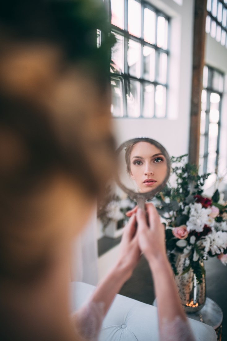 Risque Romance Bride looks at her reflection in the hand held mirror