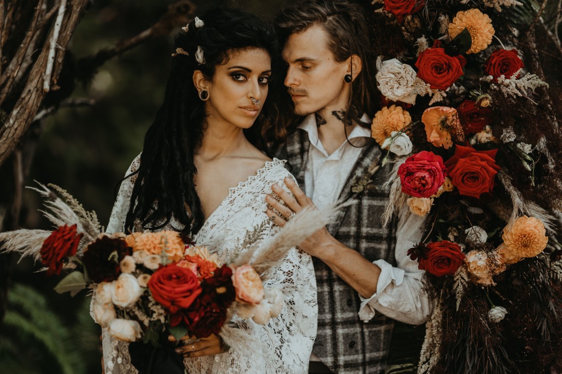 Newlyweds surrounded by red and yellow dahlias