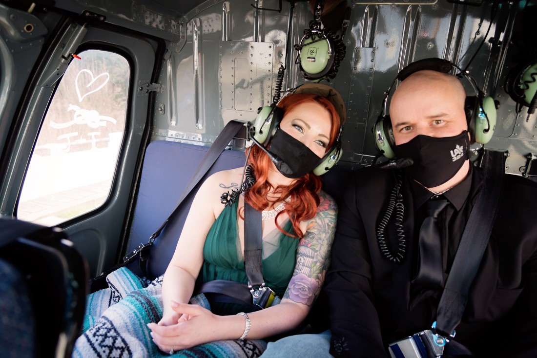 Couple wear masks in helicopter on the way to engagement session 