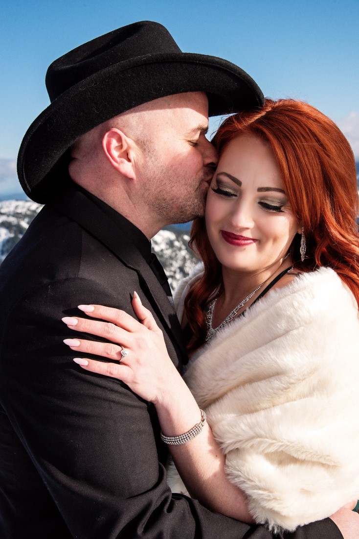 Bride to be wears white stole as fiance kisses her
