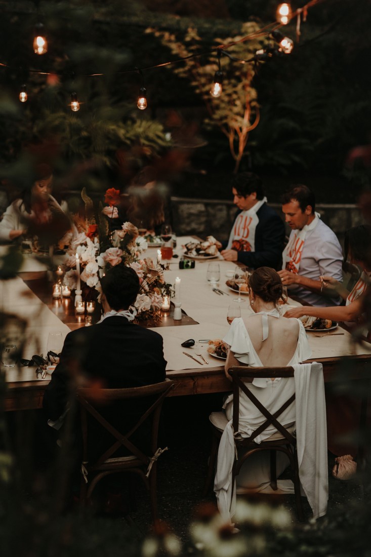 Guests sit at wedding reception table in Vancouver backyard