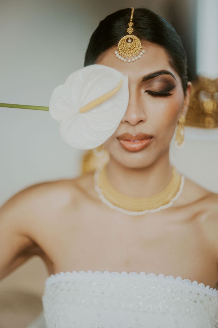 Bride holds calla lily over her eye