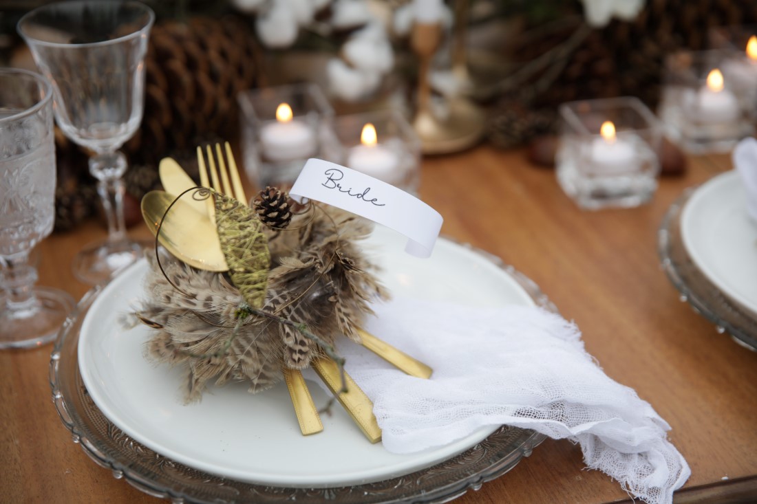Gold Cutler tied with feathers on wedding reception plate