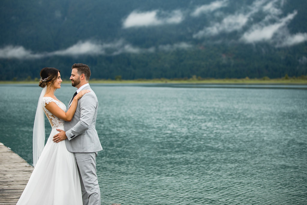 Blue waters of Pitt Lake behind bride and groom