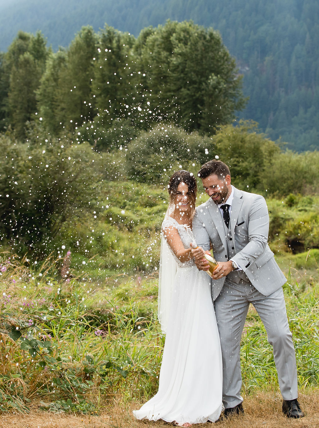 Newlyweds open bottle of champagne at Pitt Lake 