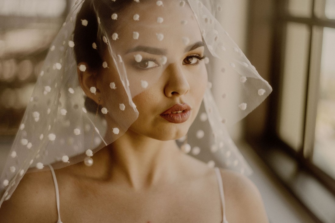 Bride looks through polka dot veil