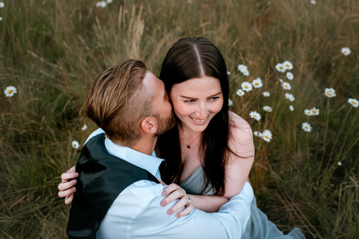 Bride smiles as groom kisses her by Leanne Sim Photo