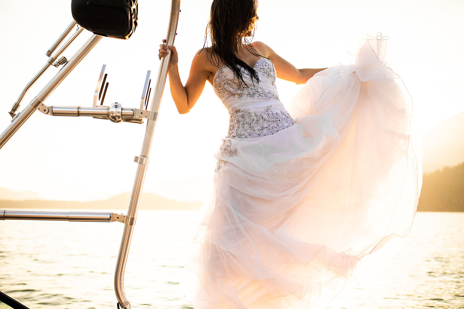 Bride swings her dress on the front of a speed boat in Vancouver