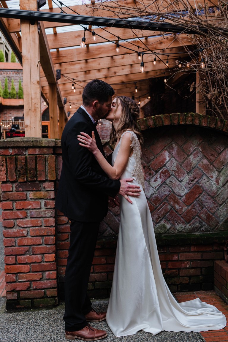 Bride and groom in front of brick wall in Victoria Inner Harbour