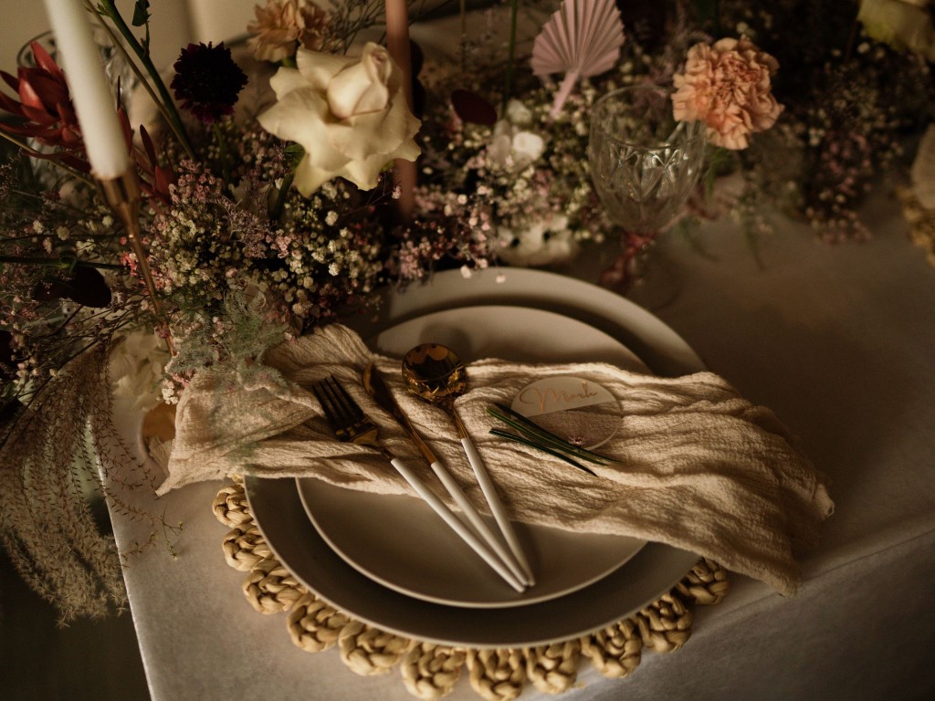 Playful table setting with floral design including roses, babies breath and palm leaves