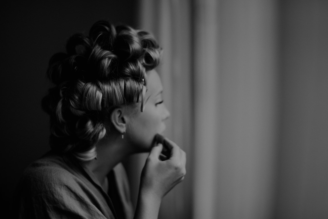 Bride with hair in curlers puts on makeup