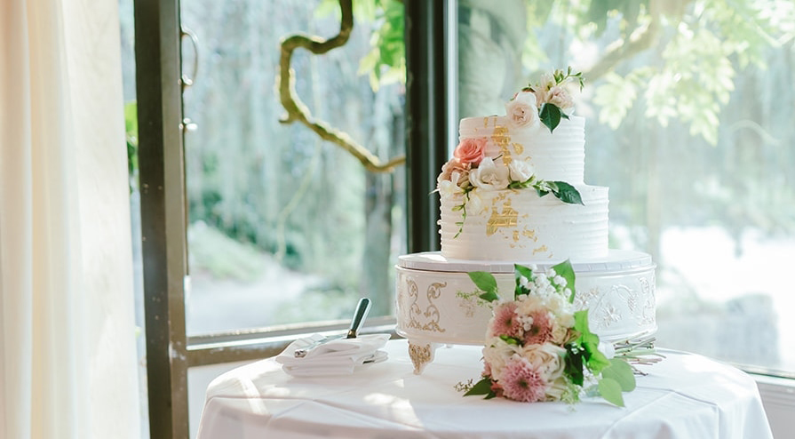 White wedding cake with greenery and pink roses