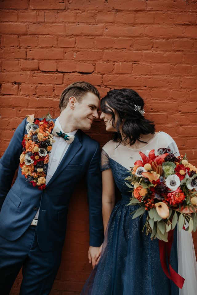 Bride and groom against red brick wall by LumiPhoto