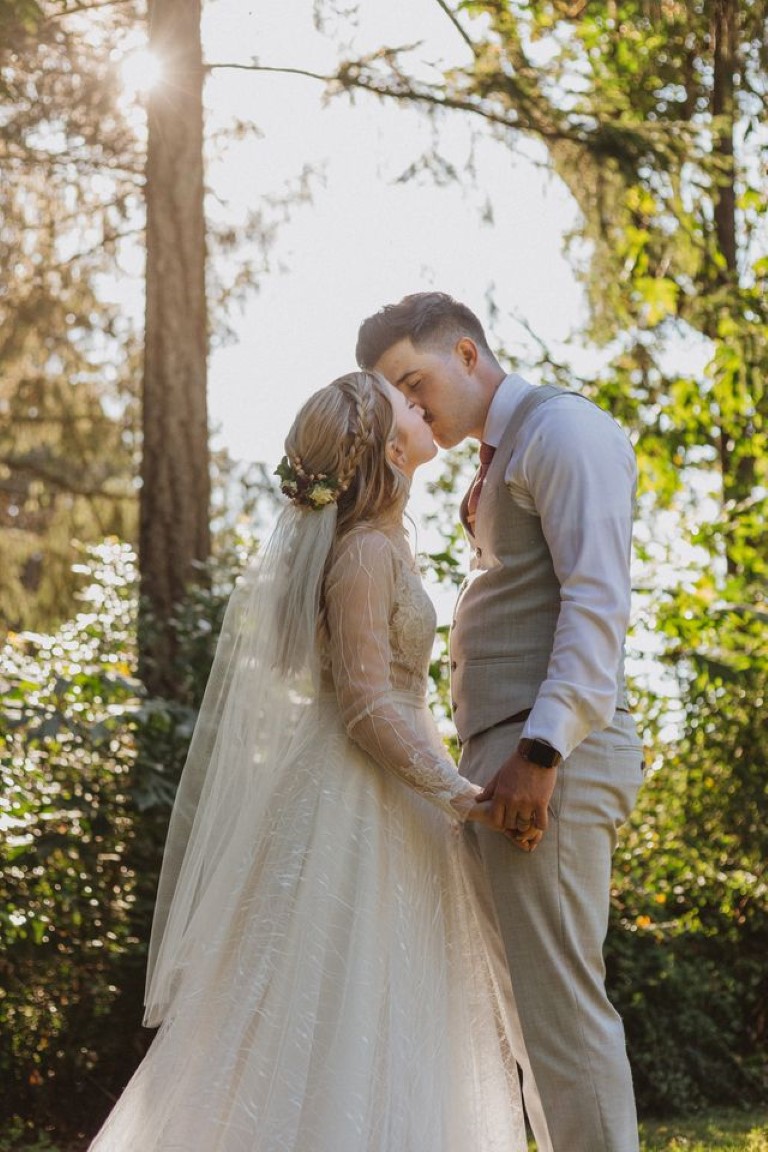 bride and groom steal away for a kiss in the vineyard