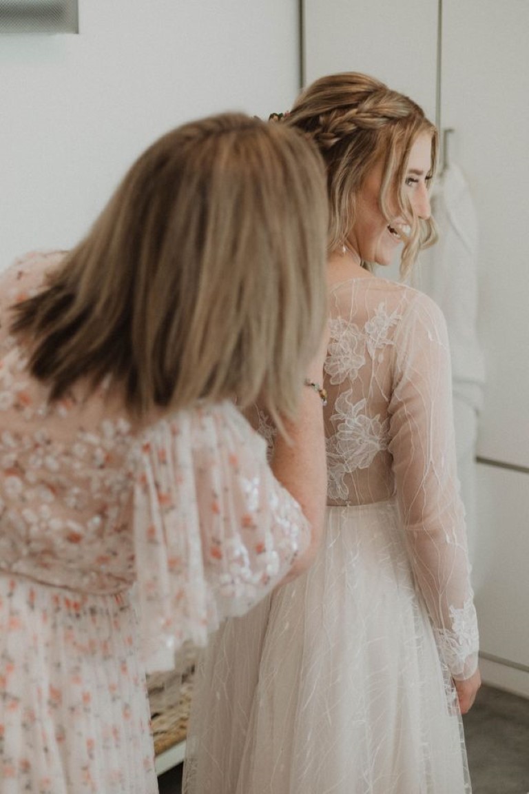 bride's mother helps her with back of dress