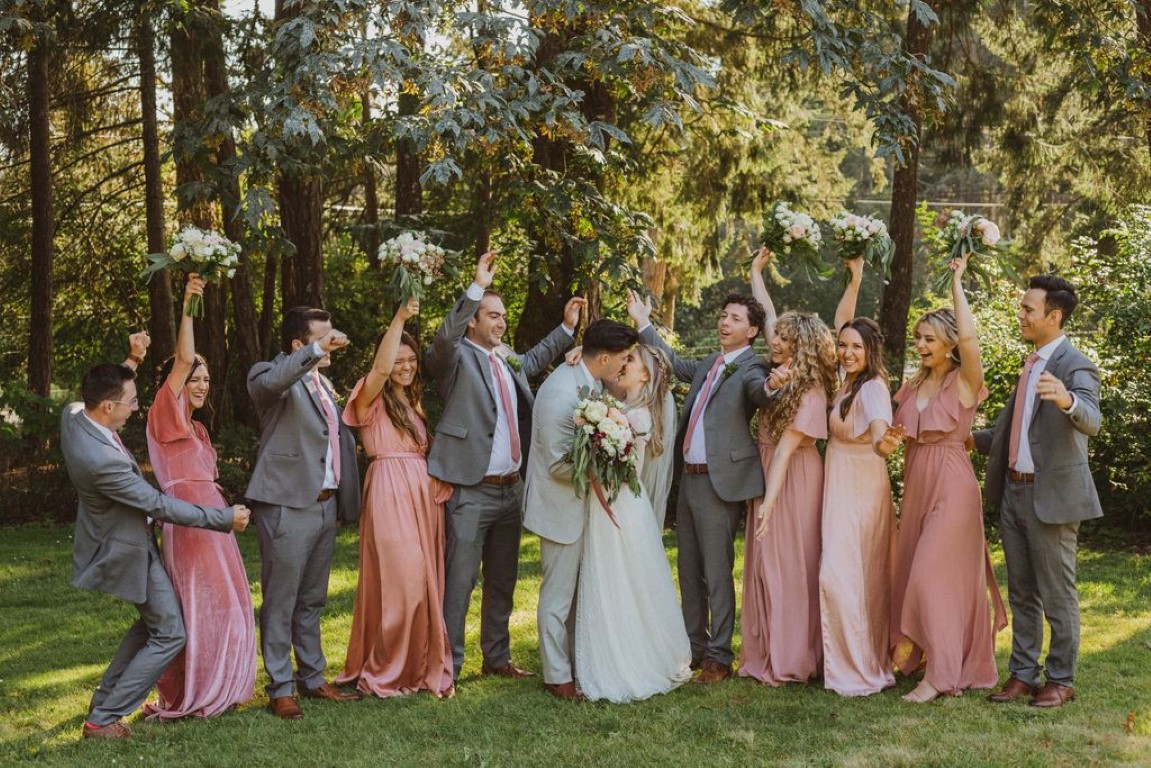 bride and groom kiss as bridal party cheers on