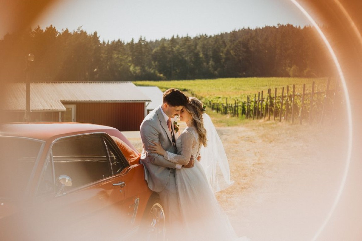 artsy shot of couple standing close to vintage classic orange car