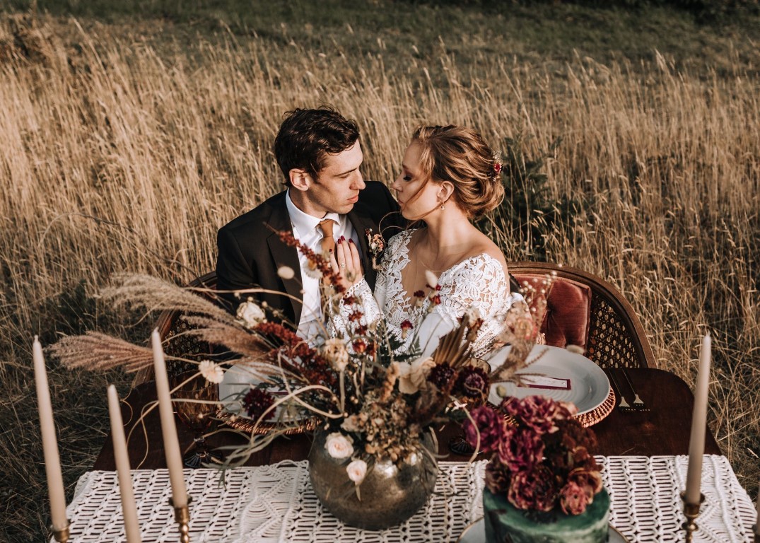 Newlyweds at sweetheart table in field of wheat