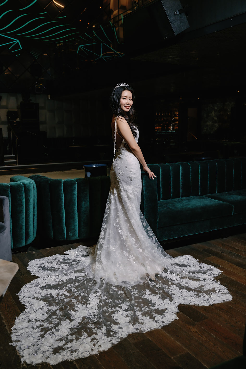 Bride in gown with train design stands in the dark