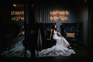 Bride sits in front of Karma is a bitch neon sign at Paradox Vancouver